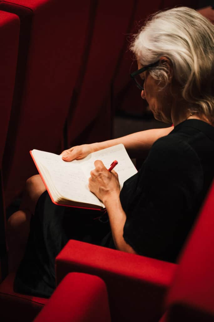 femme en train de prendre des notes dans un cahier lors d'une conférence